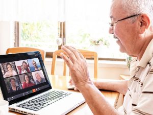 Zoom In: Keeping In Touch with Video Conferencing Senior man connecting with his family through a Zoom video conferencing app on his laptop