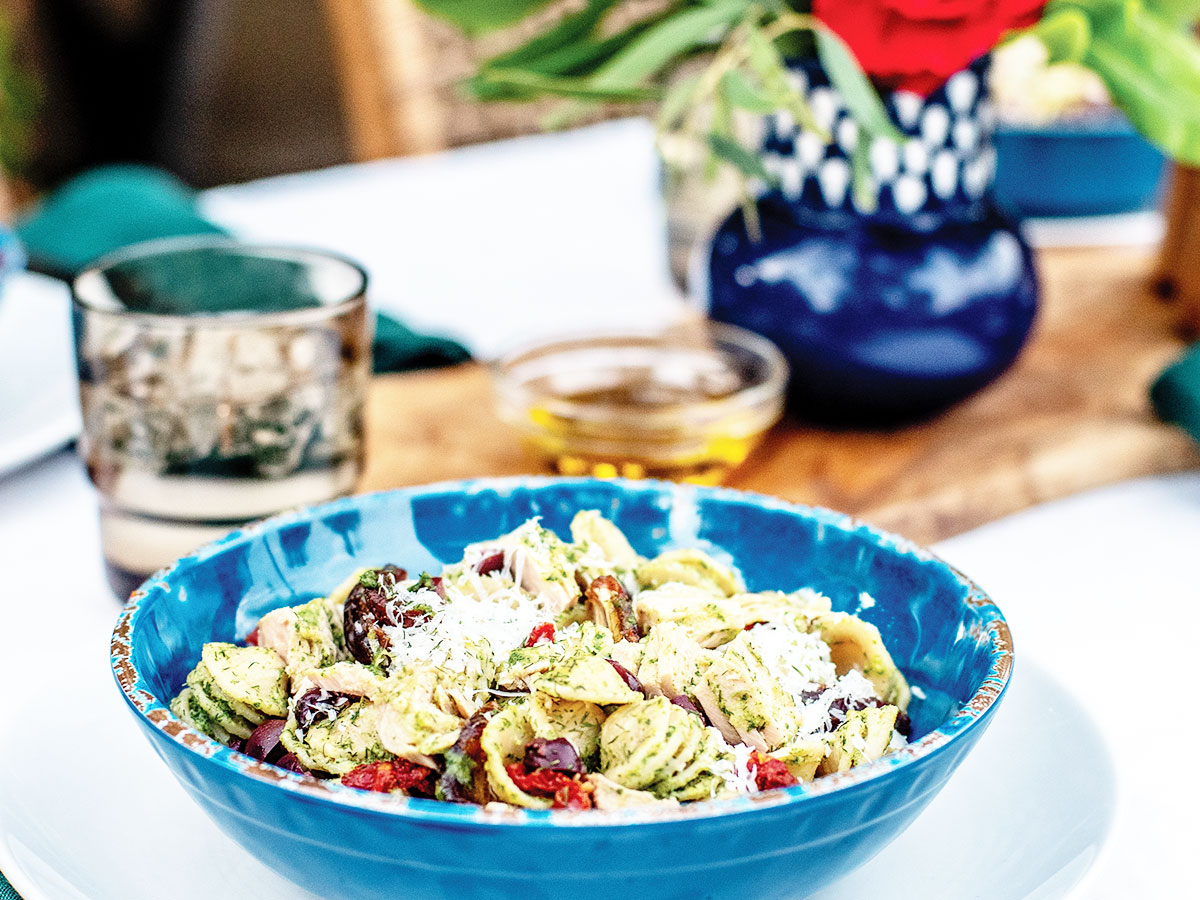 Photo of yellowfin tuna pasta salad with arugula pesto and dates served in a blue bowl.