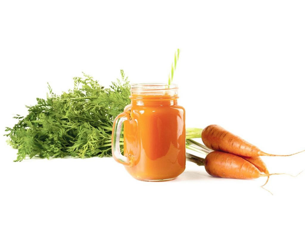 Image of carrots next to a glass of carrot juice