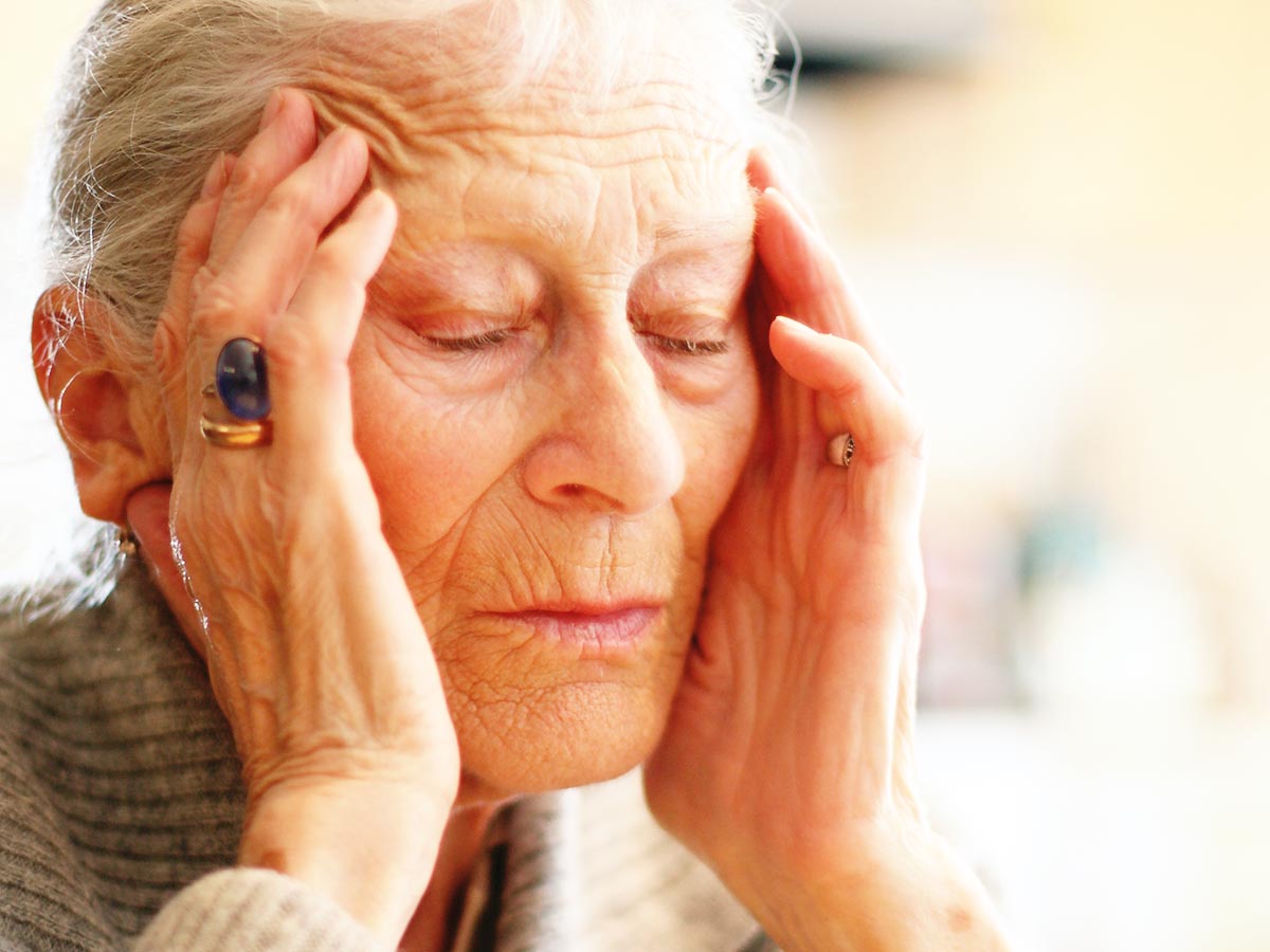 Photo of senior woman holding her head from pain