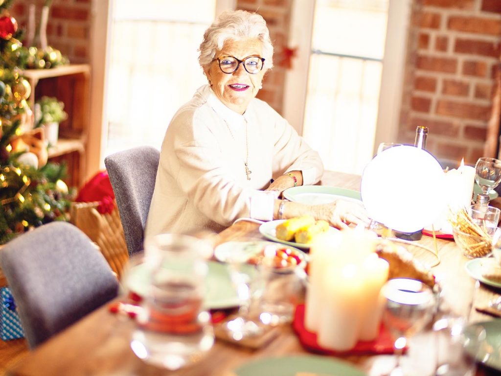 Photo of elderly woman sitting down to Christmas dinner.