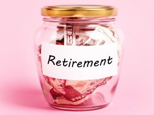Money in a jar labeled "Retirement" on a pink background
