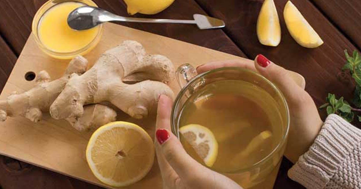 overhead photo of someone holding a cup of ginger lemon tea, to promote digestive health
