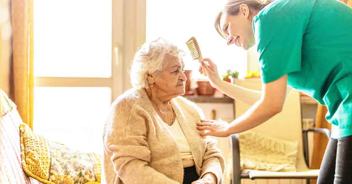 Photo of a caregiver brushing a senior woman's hair, depicting senior housing options
