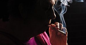 Darkened photo of a senior woman smoking recreational marijuana, for the concept of understanding the Montana marijuana law