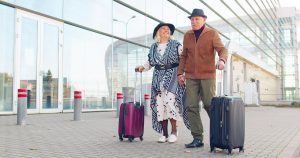 Photo of a senior couple walking with their luggage at an airport or train station