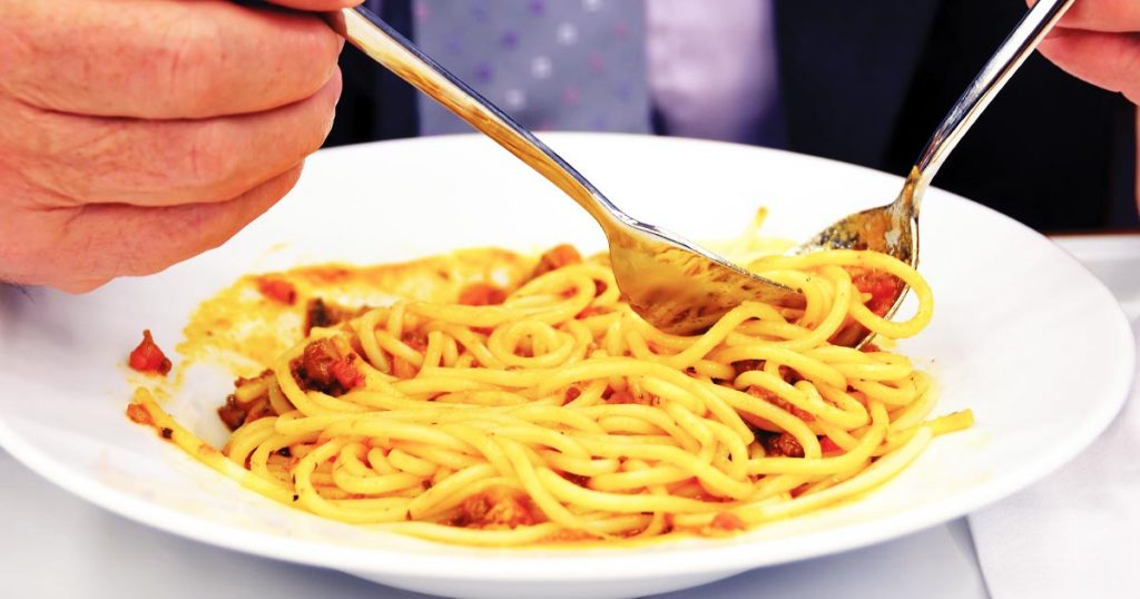 Close-up photo of a senior's hand holding a fork and twirling spaghetti from a pasta bowl. I don't think I'd be accused of kidnapping Grandad. Bribing with spaghetti? Yes. Guilty as charged.