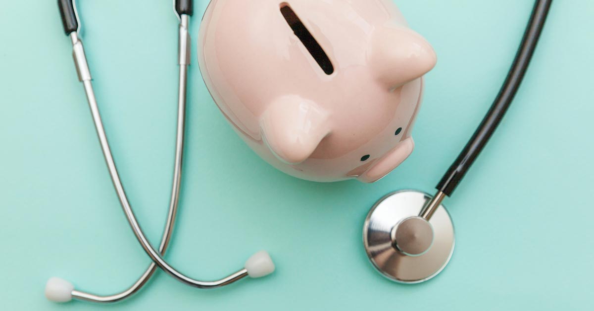 photo of a piggy bank and stethoscope on a light aqua background