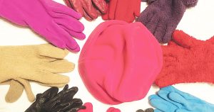 Photo of a winter hat surrounded by an assortment of colored gloves.