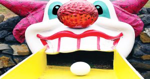 Golf ball rolling up a ramp into clown's mouth at a putt putt golf course.