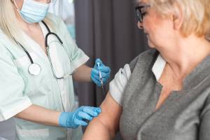 Doctor giving senior woman vaccine.
